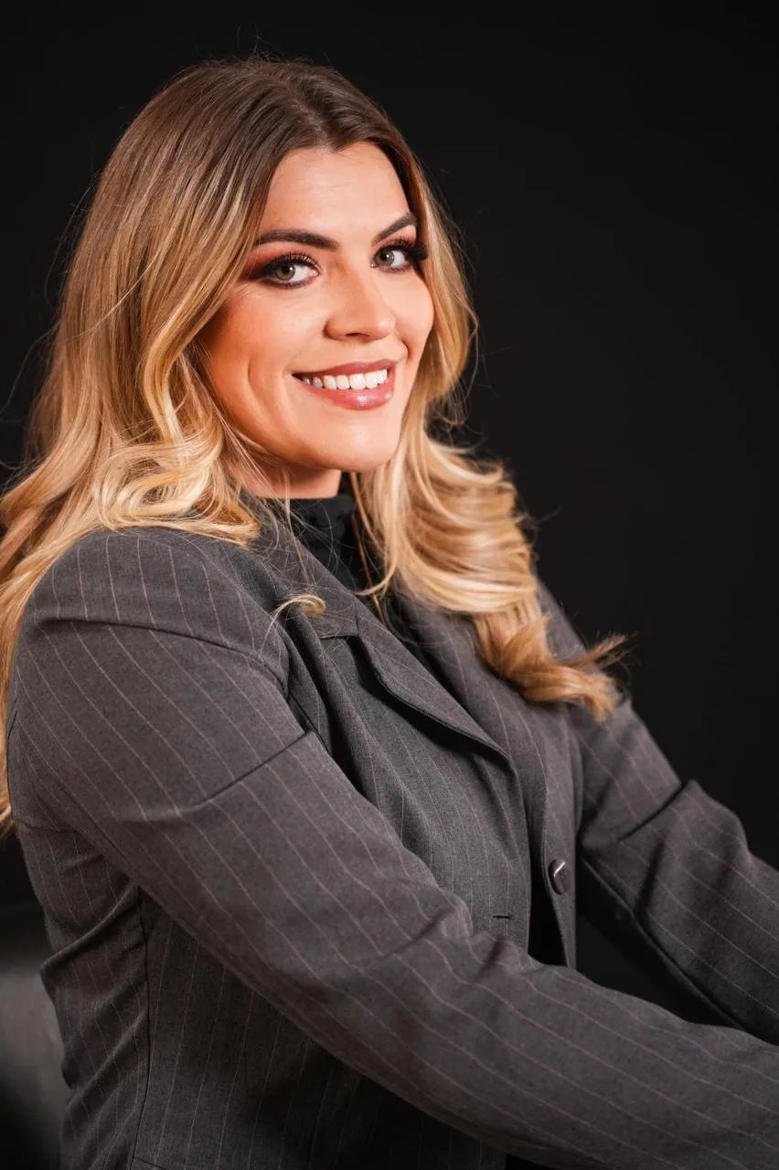 Retrato de Laura Milléo sorrindo, de blazer cinza